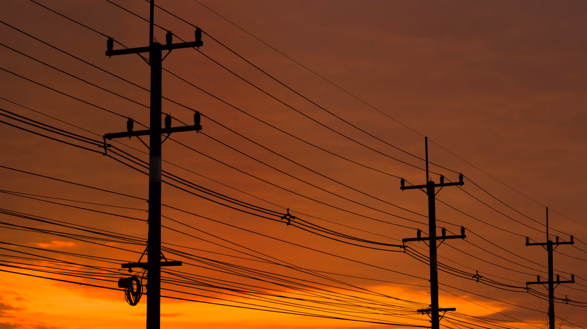 Phone power lines that are running DSL cabling with a sunset in the background